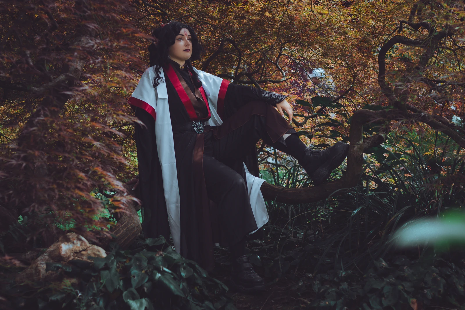 Cosplay in dunklem Gewand im Herbstwald