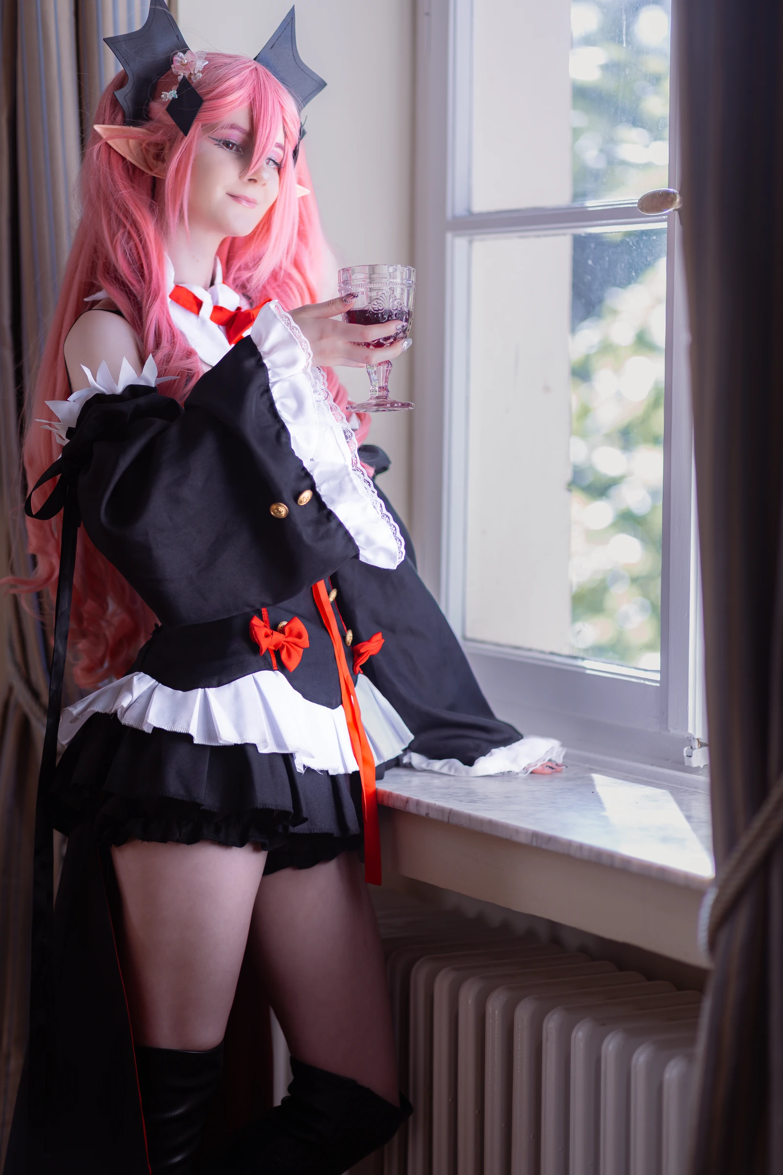 Krul-Cosplay mit Weinglas am Fenster