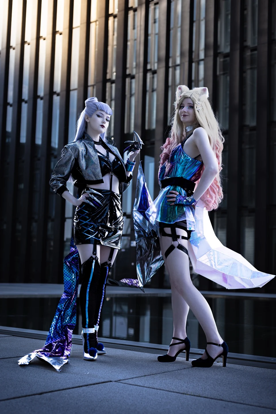 Zwei Cosplayerinnen in aufwendigen Kostümen vor moderner Architektur