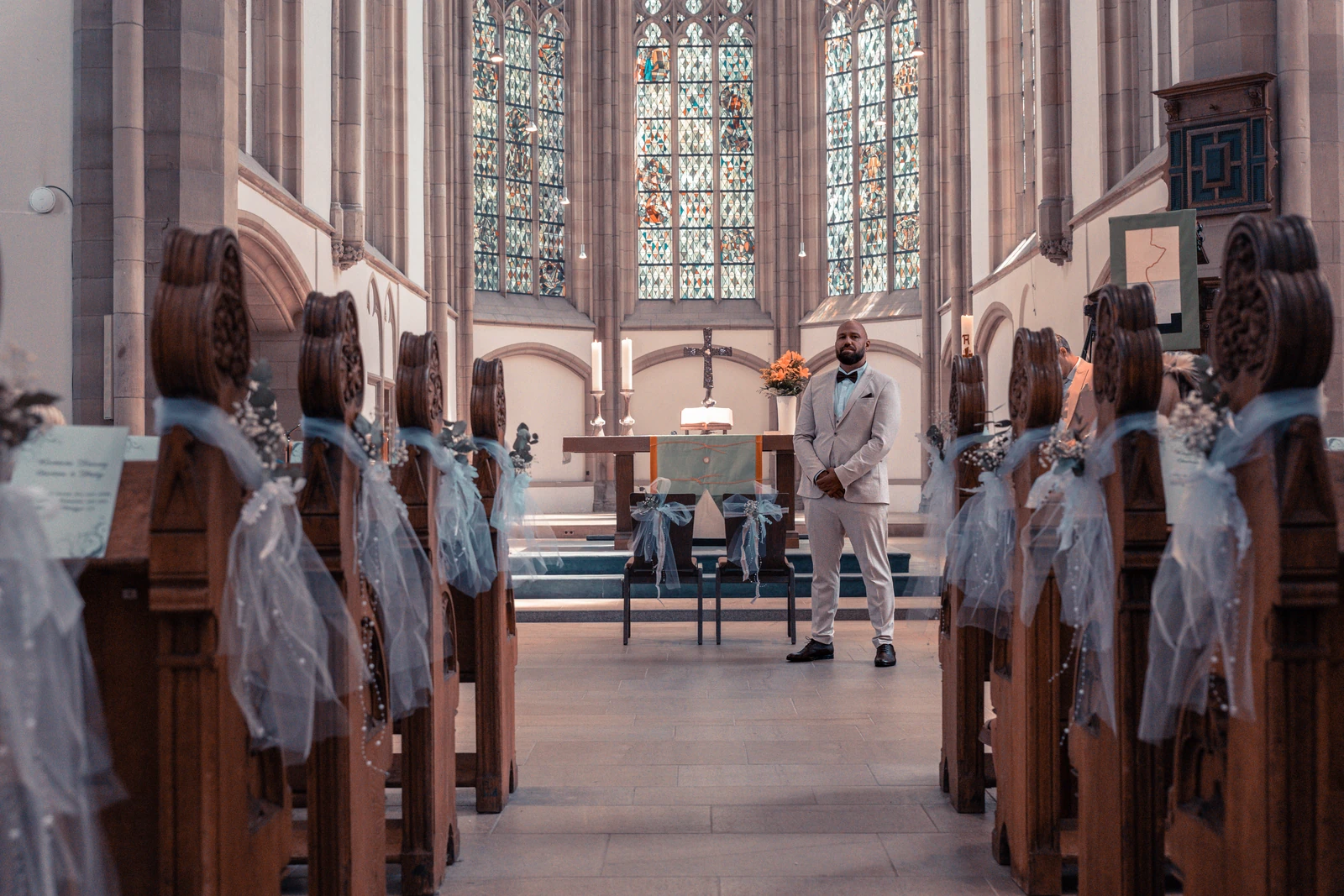 Bräutigam wartet im Mittelgang einer geschmückten Kirche